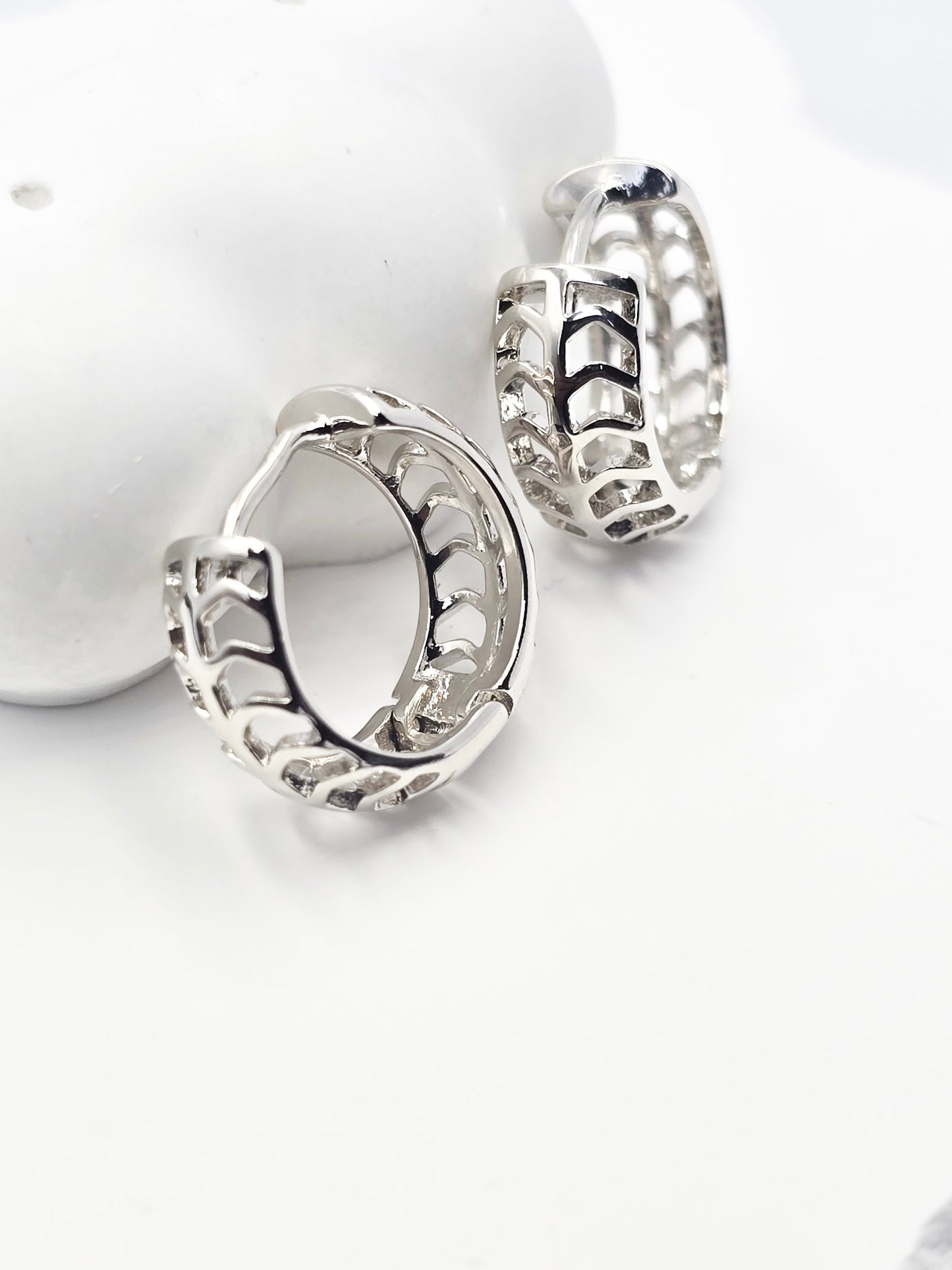 Arete Candonga, Baño en Oro 24k,Su estructura muestra un patrón calado en forma de flechas entrelazadas, que aporta un toque moderno y sofisticado. La superficie es pulida y lisa al tacto.